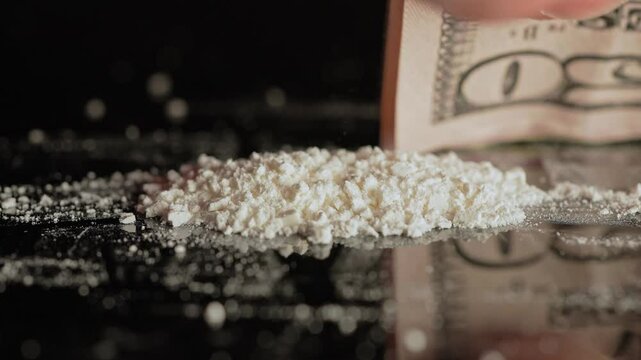 Person preparing illegal street drugs like white crystalline powder for consumption by snorting. Opioid epidemic is a major public health crisis leading to addiction, overdoses, and deaths.