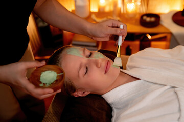 Serene ambiance of spa salon, woman customer indulges in rejuvenating with luxurious face cream massage with warm lighting candle. Facial skin treatment and beauty care concept. Quiescent