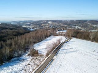 A scenic aerial view of snow-covered fields and winding roads under a clear blue sky, showcasing the tranquility of winter landscapes. © daily_creativity