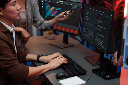 IT developers discussing with point to intelligent website development coder system running data online two screens information technology at neon light room at modern office. Infobahn.