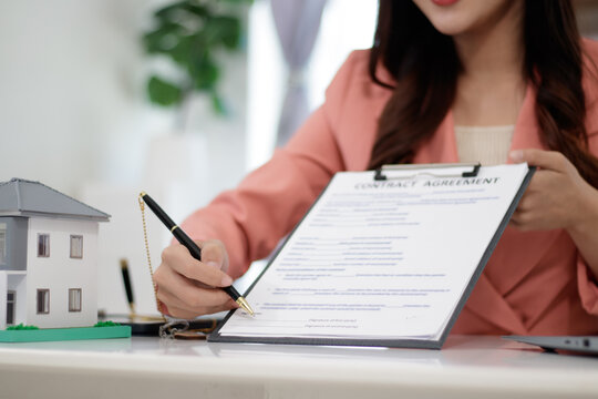 Asian businesswoman looks at Baan Diem, promises to name the house and uses a calculator to calculate the house value.