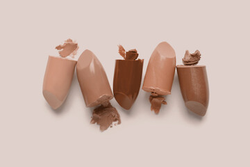 Lipsticks in mocha mousse shades on beige background, top view. Trendy color of 2025 year
