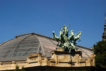 Beautiful famous monuments Quadriga statue and French flag against the blue sky in Paris, France....