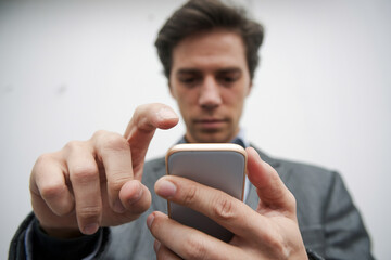 A close-up of a hand holding a mobile phone, with a white background and a side view, focusing on the hand's grip and device for a minimalist, clean look.


