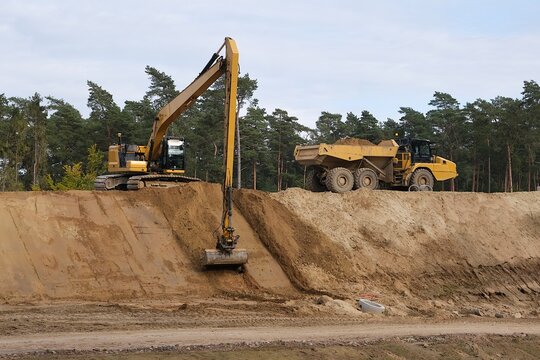 Working excavator and dumper truck on  high embankment while building road 