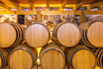 Wine barrels in the interior of cellar of winery. Wooden wine barrels in perspective. Vintage oak...