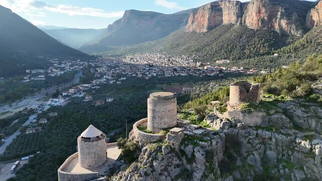 Aerial video shot of three ruined windmills on the famous Red Rock above the town of Leonidio in Peloponnese, Greece