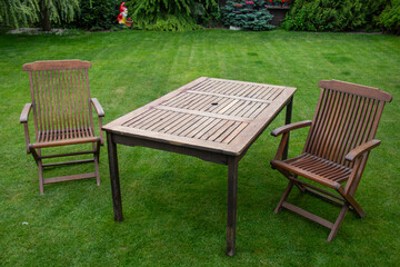 Outdoor wooden table and chairs set on a green lawn, teak furniture