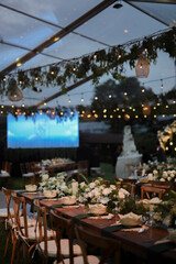 Private party table setting outdoors with hanging lamps in a tent