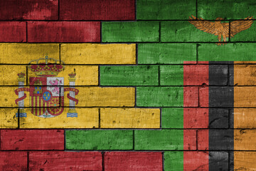 colourful painted big flag of spain and flag of zambia on a massive old brick wall background....