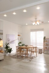 Stylish room with wooden table, chairs and houseplants. Interior design