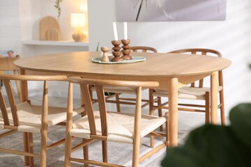 Wooden table with candles and chairs in room