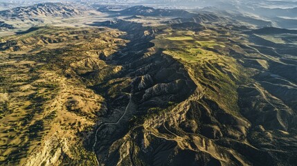 Aerial view of rugged mountain terrain with rolling hills and valleys under clear skies Copy Space