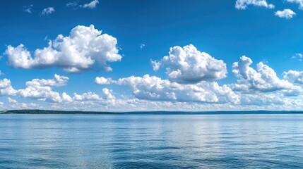 Obraz premium Calm lake or sea under a clear blue sky with fluffy clouds and reflections on water Copy Space