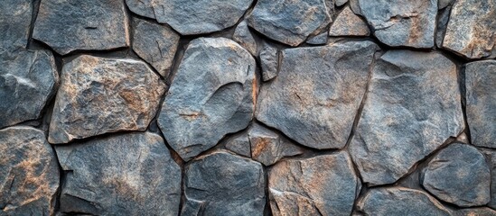 Fototapeta premium Textured stone wall background with irregular slate rocks in varying shades of gray and brown suitable for various design applications Copy Space