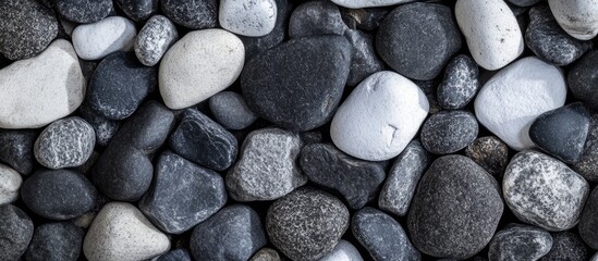 Pebble stones in various shades of gray and white arranged on a flat surface with Copy Space for text placement
