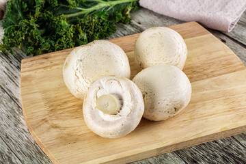 White champignon mushrooms heap over board