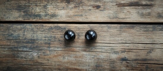 Stylish black stud earrings displayed on rustic wooden background with ample copyspace for customizable text and promotional content