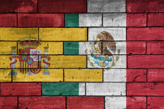 colourful painted big flag of spain and flag of mexico on a massive old brick wall background. concept