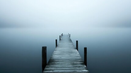 Obraz premium Foggy pier extending into calm water with reflection and muted colors Copy Space