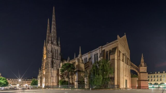 Cathedrale Saint-Andre de Bordeaux night timelapse hyperlapse with twin spires. Illuminated buildings and trees on the Pl. Pey Berland square create an evening urban atmosphere. Bordeaux, France