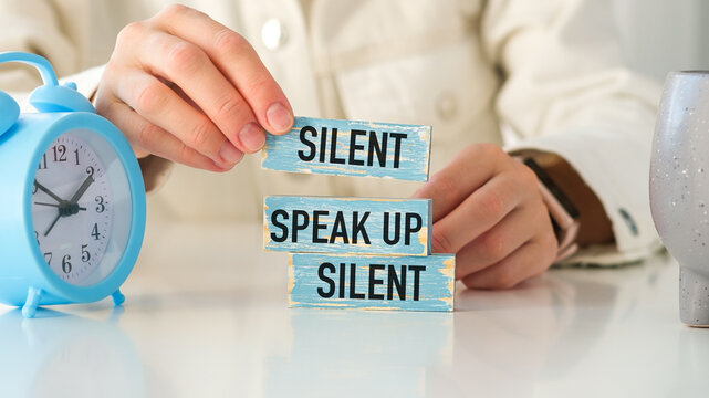 Words Silent speak silent Inscription on wooden blocks and hands of a woman.