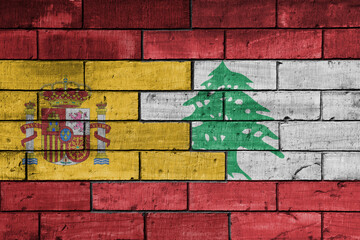 colourful painted big flag of spain and flag of lebanon on a massive old brick wall background....