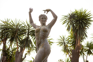 Looking up at statue in honour of Flamenco singer and dancer Lola Flores with palm trees on either...