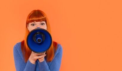 Fototapeta premium A young woman with vibrant red hair holds a blue megaphone while expressing excitement