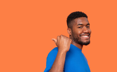 Man smiling and giving a thumbs up against a bright orange background