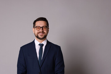 Portrait of banker in glasses on grey background, space for text