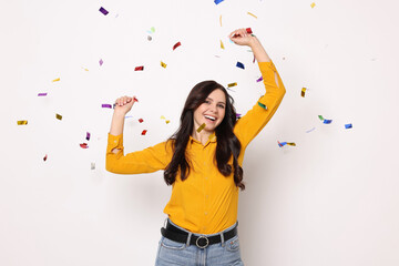 Fototapeta premium Happy woman under falling confetti on white background. Surprise party