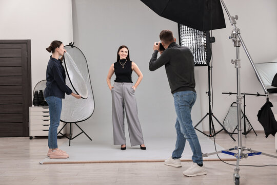 Photographer and assistant working with model in professional photo studio