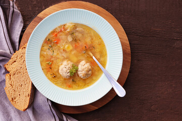 Soup with meatballs on dark background, gray linen napkin. Healthy meatball soup with vegetables. Top view