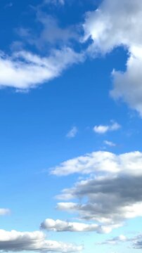 Amazing blue sky with slowly moving clouds above the head. Low angle view at the white light clouds. Vertical video.