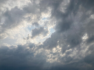 Fototapeta premium Dramatic sky filled with dense, textured clouds, covering frame Sunlight filters through breaks, creating contrast and golden light beams Artificial image alteration suggests digital editing or cro