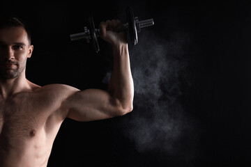 Man with talcum powder on hand training with barbell against black background. Space for text