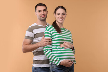 Pregnant woman and her husband on beige background