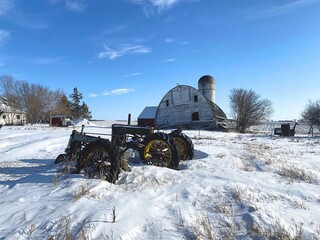 A once bustling farm, now abandoned, with its tractors and barn