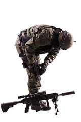 Special Forces Soldier in Tactical Gear Adjusting Equipment Beside Rifle on White Background