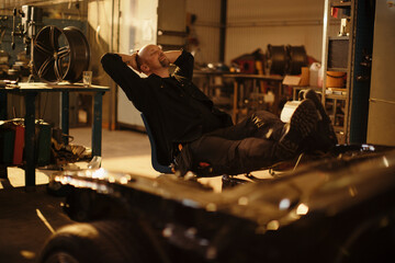 Male mechanic sitting relaxed in chair at workshop