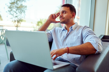Fototapeta premium Businessman using laptop computer in office, taking a break and looking out the window, thinking about future opportunities