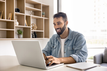 Young smiling Hispanic businessman, student or office employee studying, e-learning, searching...