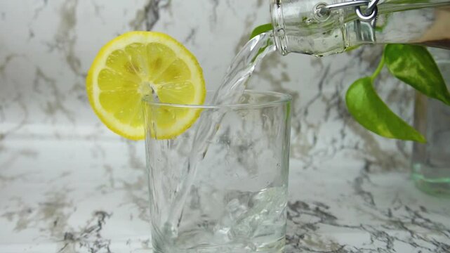 Closeup of tap water poured into glass lemon slice on marble clean white background. Purity, nature, health, diet, detox