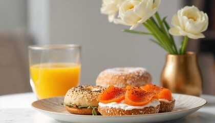 breakfast plate with bagel topped with cream cheese and smoked salmon, glass of orange juice, donut, and white tulips in a vase
