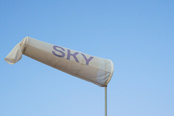 White windsock with SKY printed on it under a clear blue sky.