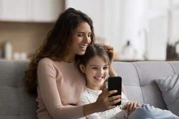 Shooting selfie. Smiling millennial single mother adorable tween age child daughter cuddle on comfy...