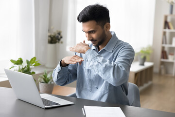 Sign language interpretation. Focused millennial male teacher interpreter sitting by notebook...