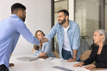Group of professionals engages in friendly and positive interaction during business meeting, shake...
