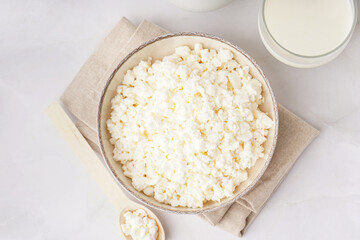 Bowl with tasty cottage cheese on light background
